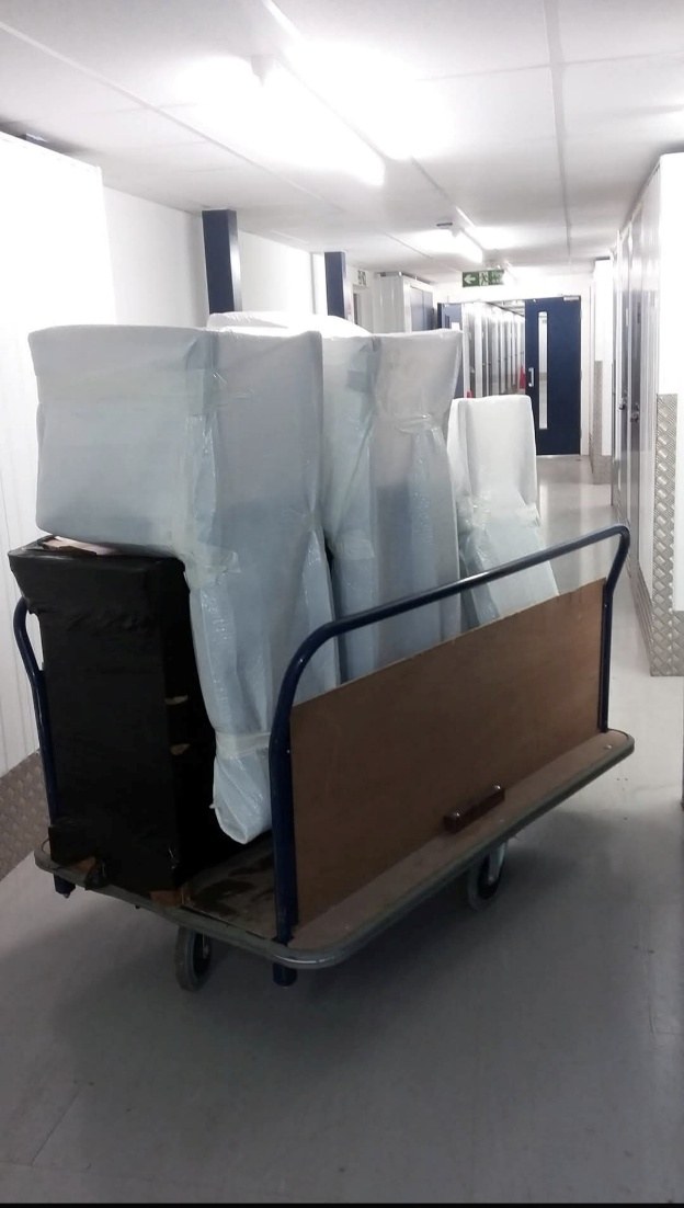 Wrapped furniture on trolley in storage corridor